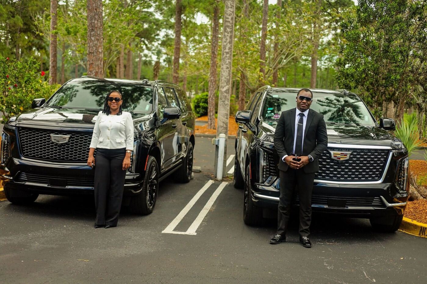 Owner and female chauffeur standing beside two black Cadillac Escalade ESVs