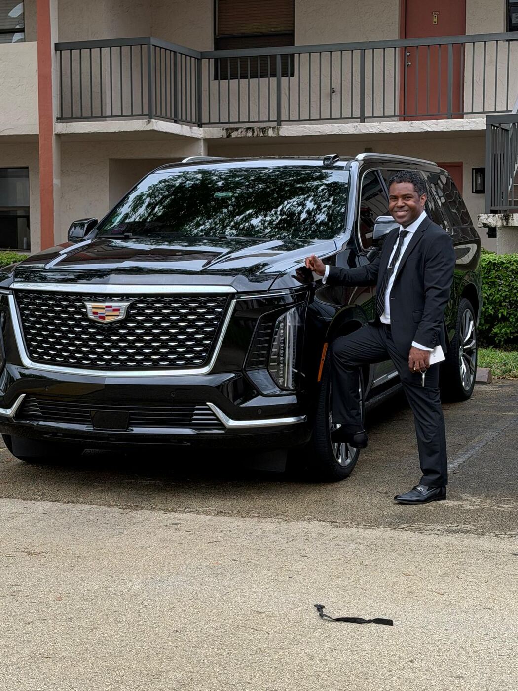 MS Luxury Black Car owner in a suit beside a new black Cadillac Escalade